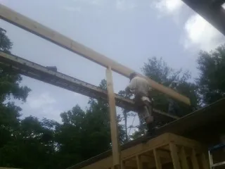 Carpenter setting a ridge beam over a new addition frame — Ice Dam Removal by Roofing Brothers in Three Bridges