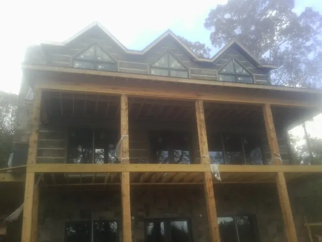 Dormers and porch framing on a large log home under construction — Roof Coating work by our crew in Three Bridges