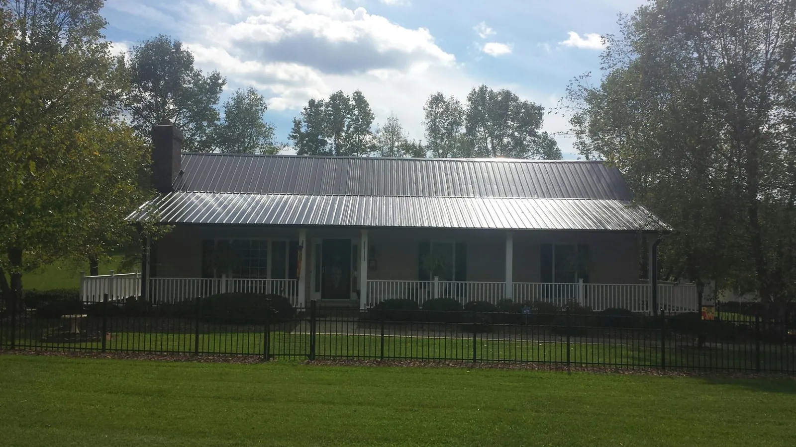 Gray metal roof on a brick ranch with a full width front porch — Gutter Guard Installation work by our crew in Three Bridges