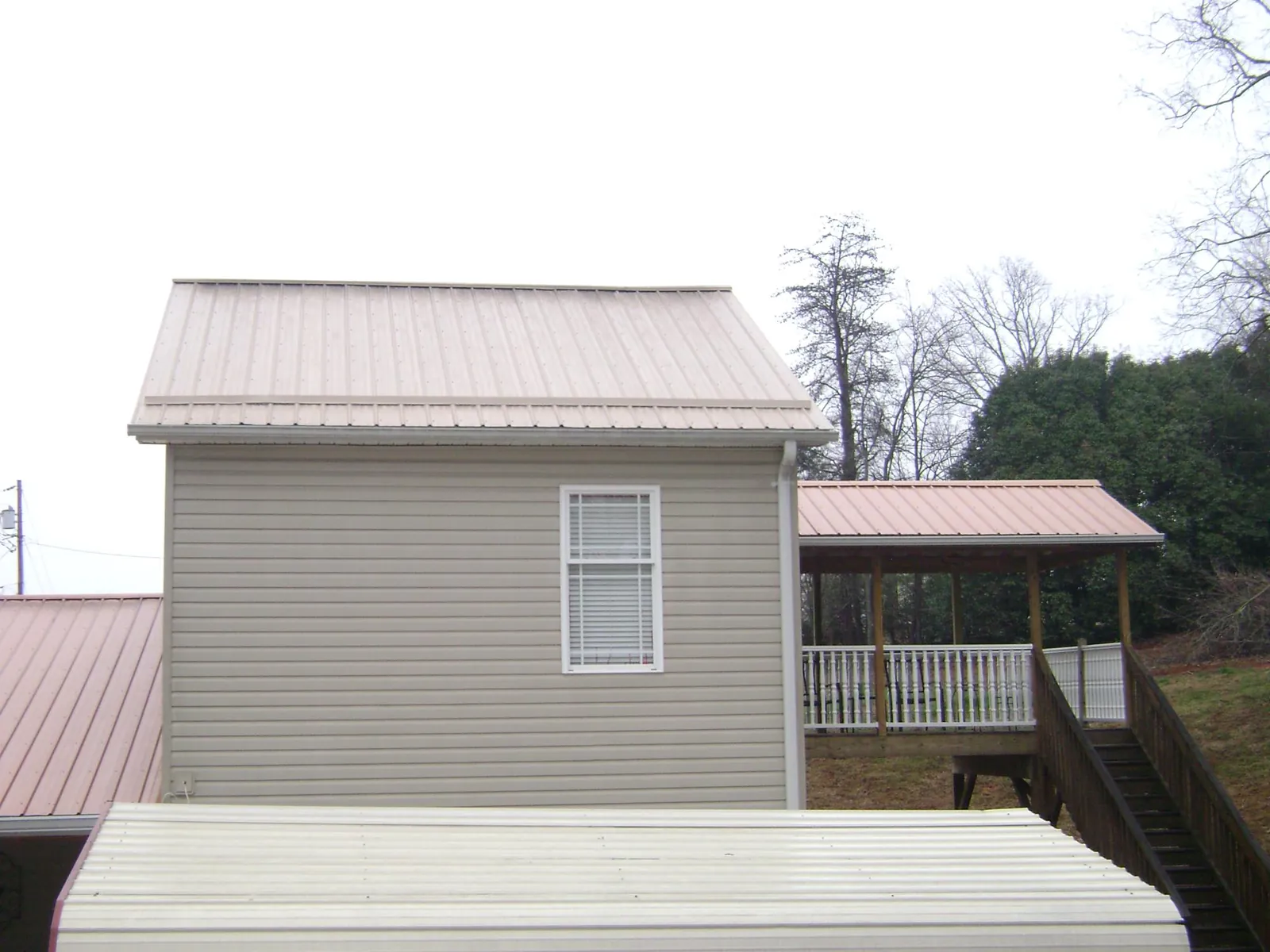 Tan metal roofs on a two story addition and attached porch, from a Roof Replacement job in Three Bridges